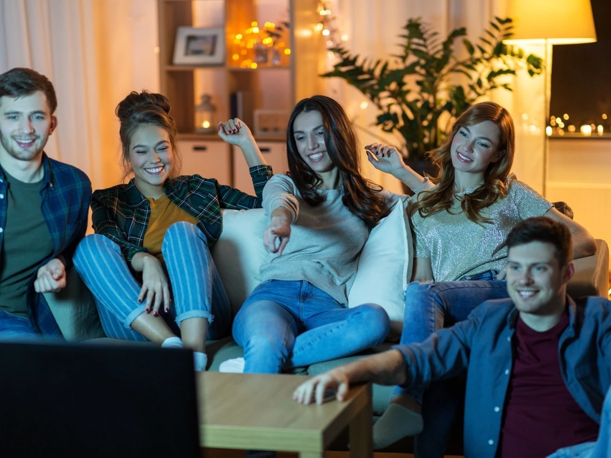 Freunde schauen abends gemeinsam auf einem Smart-TV im Wohnzimmer fern