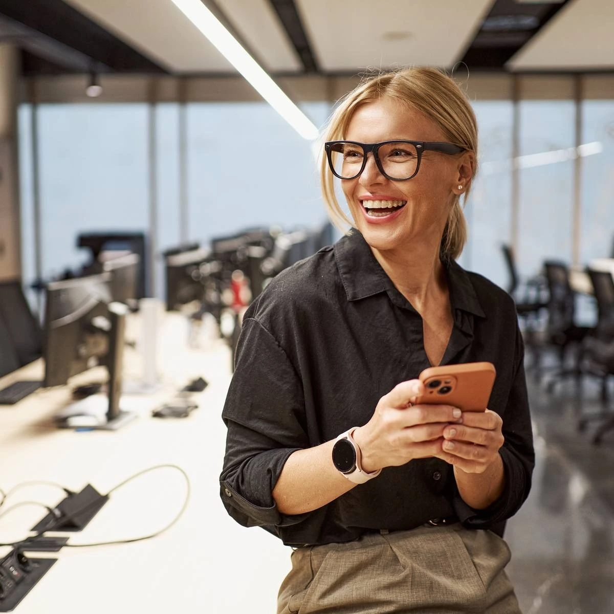 Unternehmerin im Büro beantwortet eine Presseanfrage am Smartphone